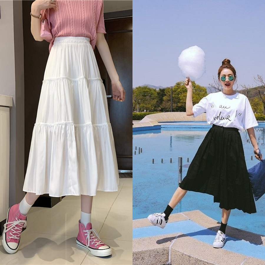 Cô gái dạo biển với chân váy maxi màu hồng pastel và giày sneaker trắng năng động