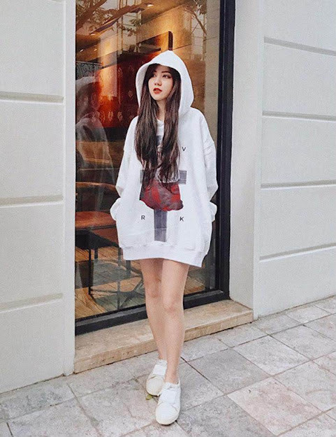 Cô gái diện áo hoodie màu hồng, quần đen và giày thể thao trắng