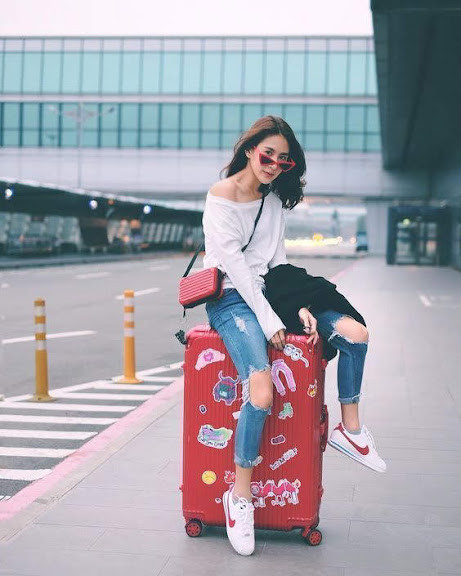 Cô gái diện áo khoác đen, áo crop top trắng, quần jeans xanh và giày thể thao Nike đen trắng