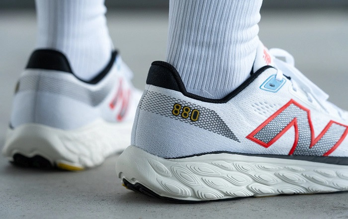 Đôi giày New Balance 880 v14 màu xám và cam đang được đặt trên một bề mặt