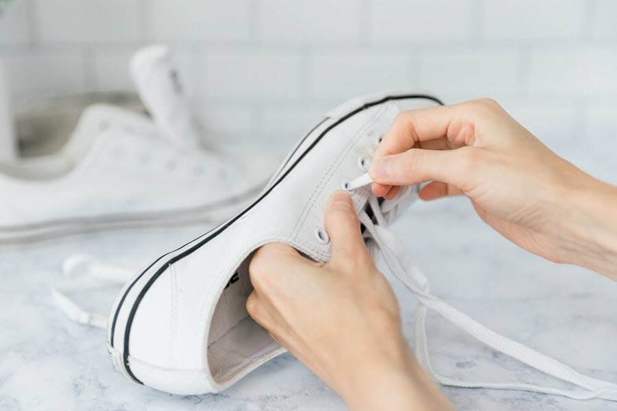 Giày thể thao đang được chuẩn bị trước khi cho vào máy giặt, dây và đế được tháo rời