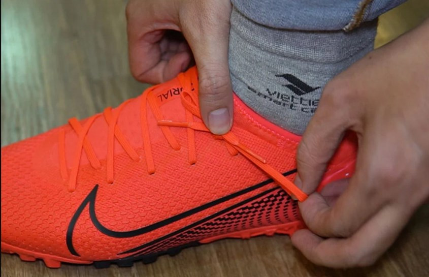 Hình ảnh mô tả kỹ thuật giấu nút thắt dây giày đá bóng, hạn chế vướng víu và đảm bảo an toàn tối đa khi vận động.