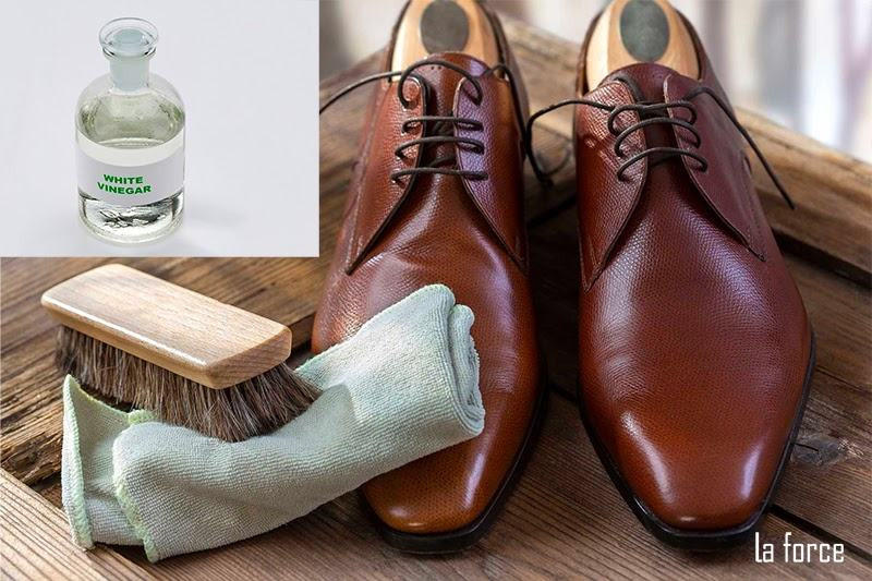 Một chai giấm ăn và khăn sạch đặt cạnh đôi giày da bị tróc, minh họa phương pháp xử lý vết bong tróc bằng nguyên liệu tự nhiên.