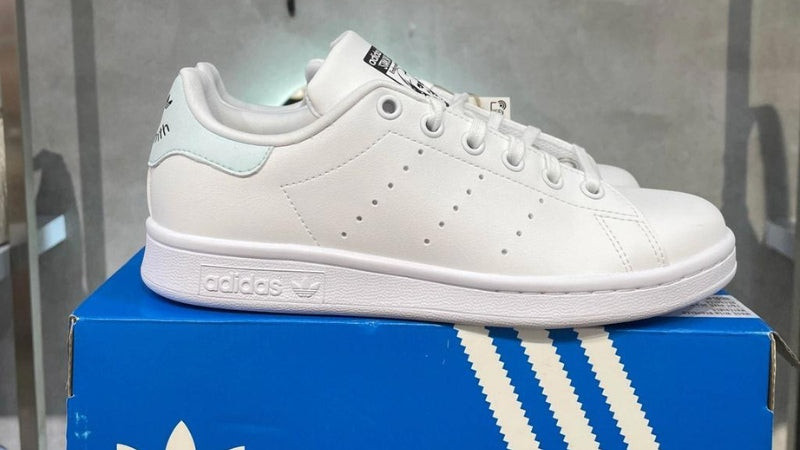 Một đôi giày thể thao Adidas Superstar trắng với ba sọc đen đặc trưng, biểu tượng của hãng giày thể thao Đức