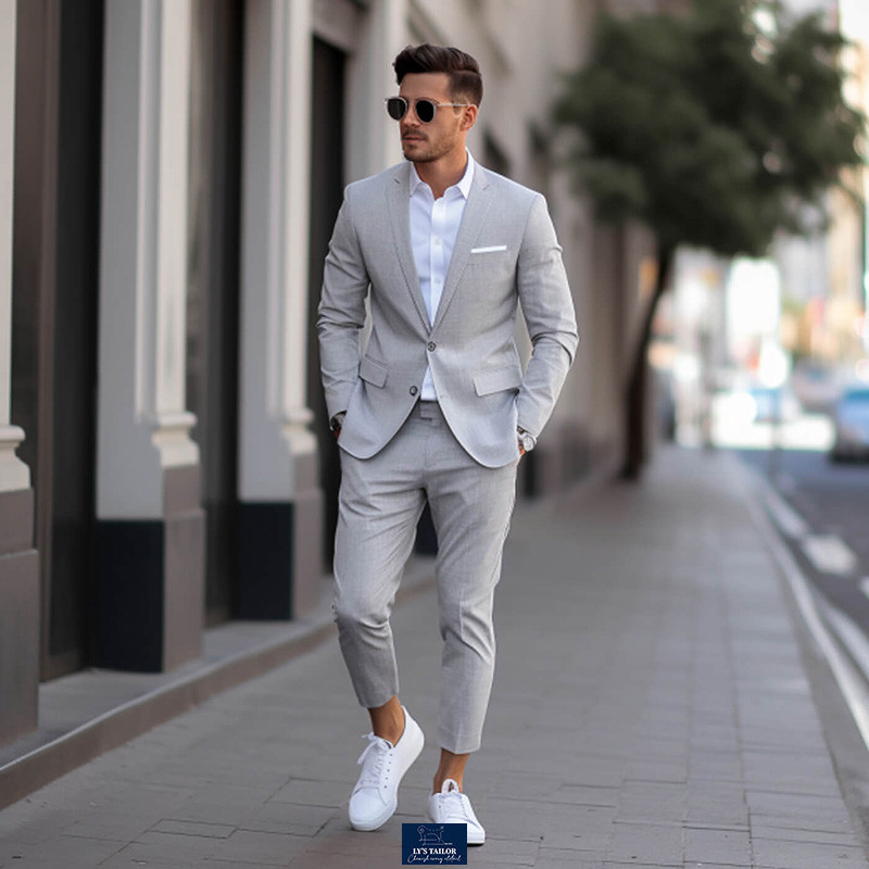 Người đàn ông mặc vest kẻ sọc xám với quần ống lửng và giày sneaker trắng, thể hiện sự thoải mái và năng động