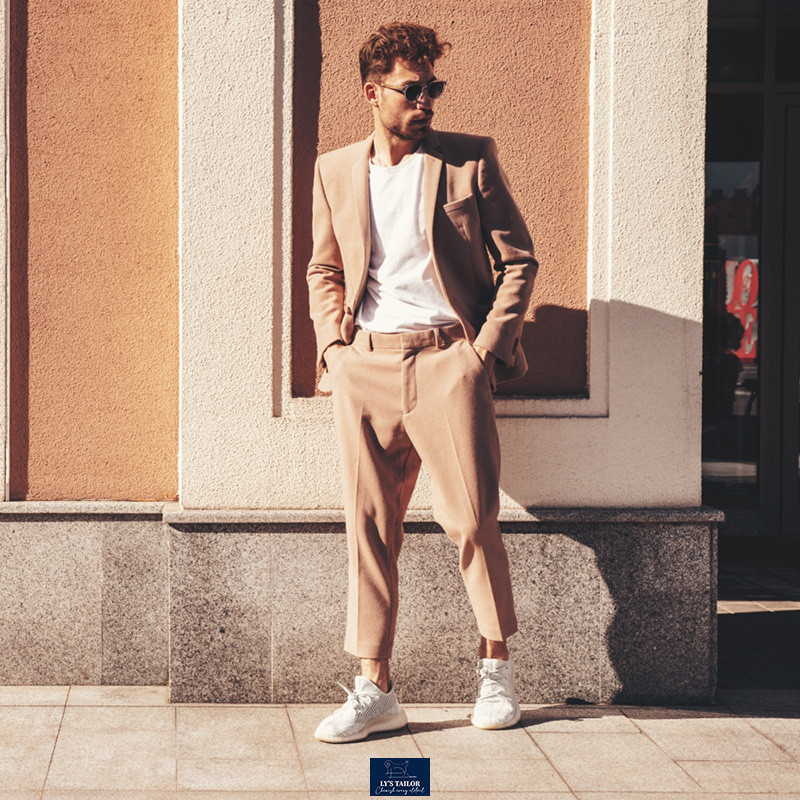 Người đàn ông mặc vest màu be, áo phông trắng và giày sneaker trắng, phong cách thanh lịch, phù hợp mùa hè