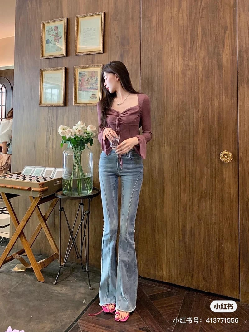 Người mẫu mặc quần ống loe màu be, áo sơ mi kẻ và sandals cao gót buộc dây màu hồng nữ tính