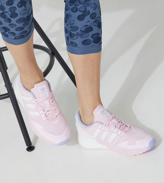 Người phụ nữ năng động với giày thể thao Adidas nữ ZX 1K Boost trắng, mang lại cảm giác thoải mái suốt cả ngày dài hoạt động.