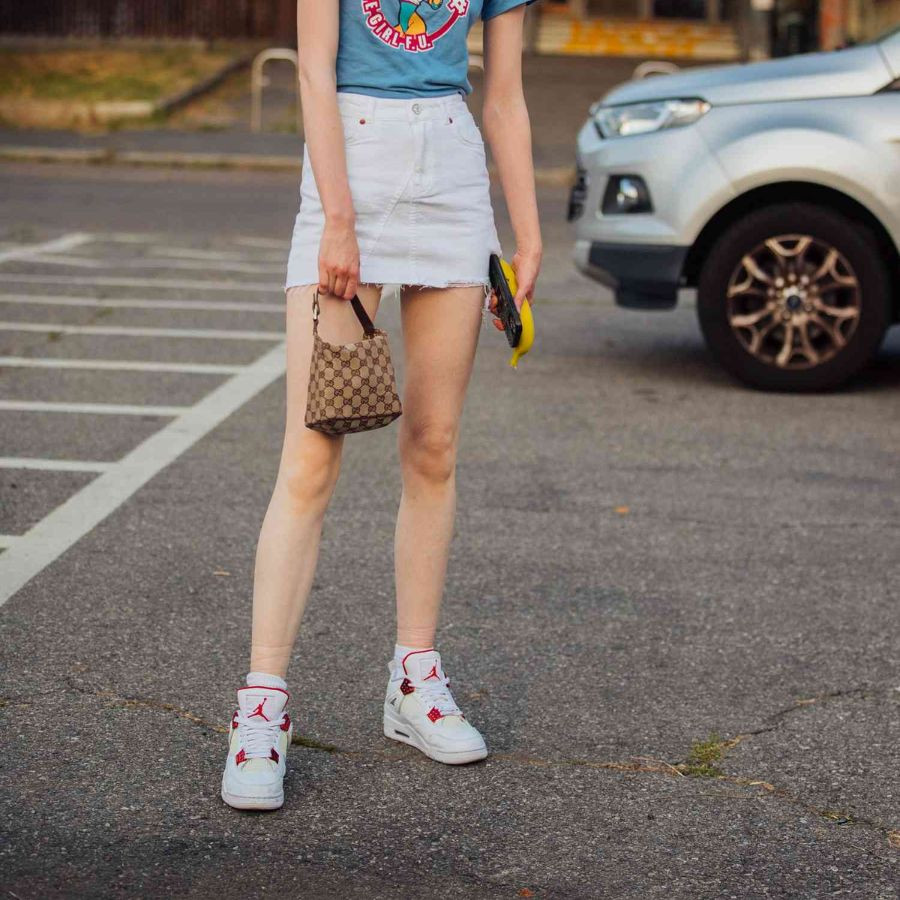 Phong cách năng động với váy ngắn kẻ sọc và giày thể thao màu đen, phù hợp cho mùa hè.