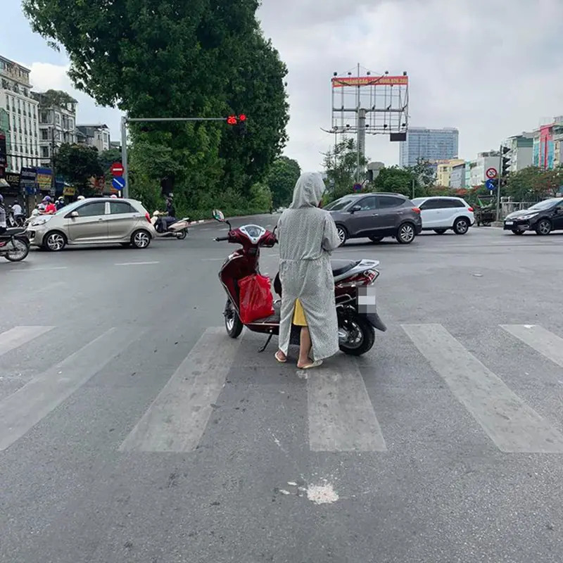 Người phụ nữ mặc đồ chống nắng kín mít lái xe máy Lead trên đường phố đông đúc