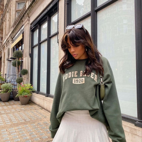 Người mẫu mặc áo sweater trắng phối chân váy xếp ly ngắn màu xám